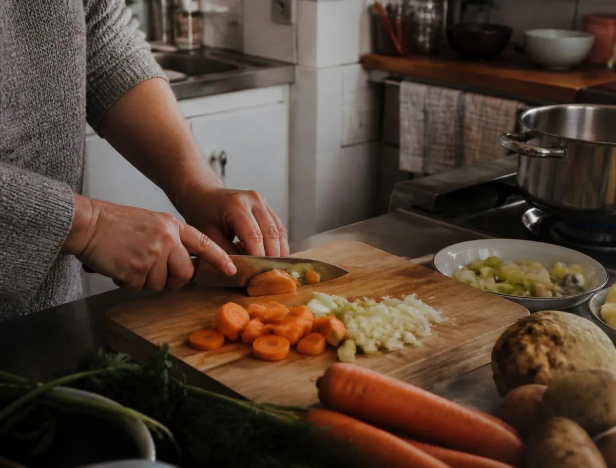 Kochen und Haushaltsführung im Alltag Betreuerin bereitet in der Küche eine frische Mahlzeit zu
